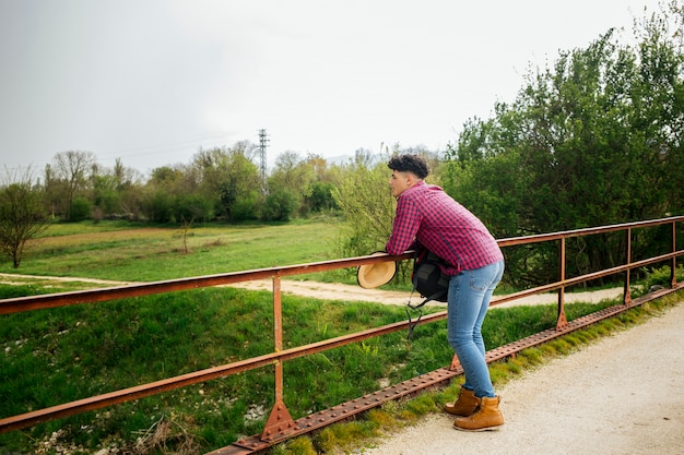 Uomo che si appoggia sulla ringhiera guardando la natura