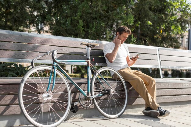 Uomo che si distende su una panchina accanto alla sua bicicletta