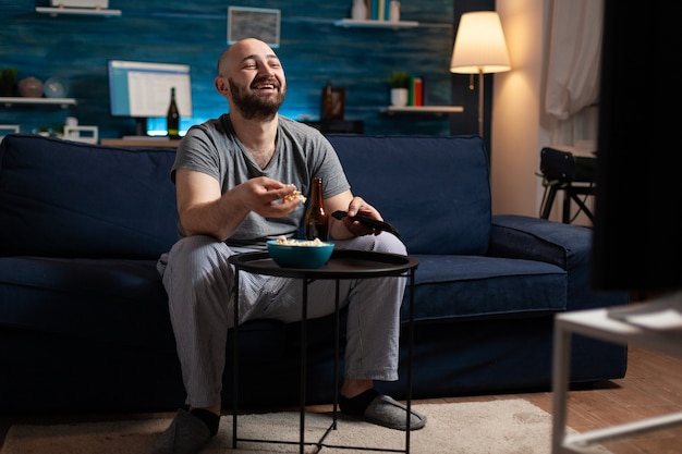 Uomo che si diverte a rilassarsi guardando le serie di commedie televisive a casa