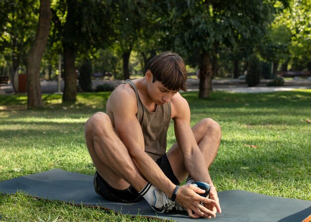 Uomo che si estende in natura sulla stuoia