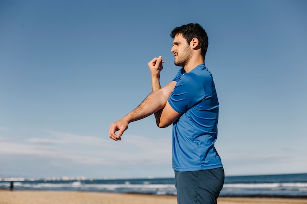 Uomo che si estende in spiaggia