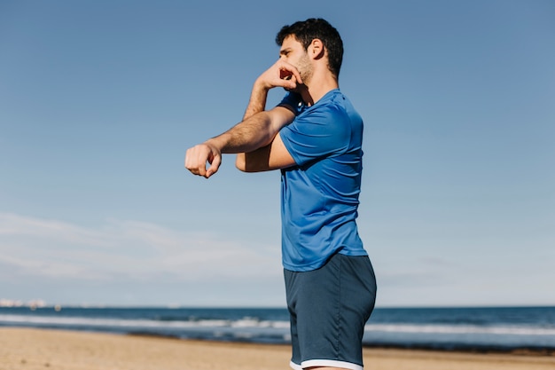 Uomo che si estende in spiaggia