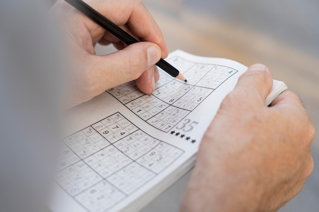 Uomo che si gode da solo un gioco di sudoku su carta