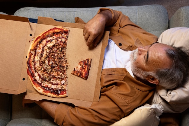 Uomo che si gode una pizza mentre è a casa da solo