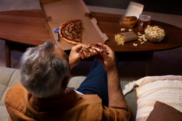 Uomo che si gode una pizza mentre è a casa da solo