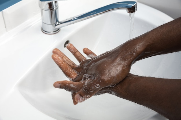 Uomo che si lava accuratamente le mani con sapone e disinfettante, primo piano.