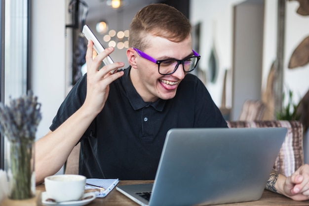 Uomo che si siede con lo smartphone al tavolo