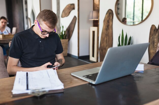 Uomo che si siede con lo smartphone nella caffetteria