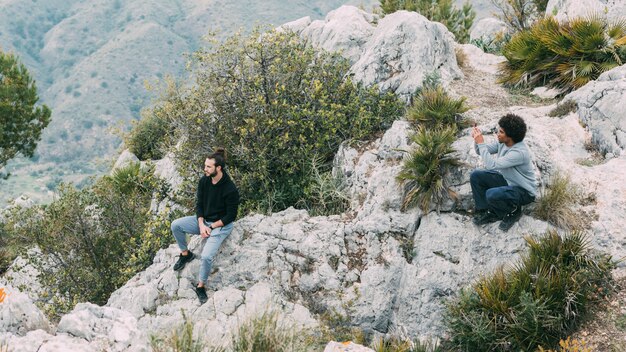 Uomo che si siede sulla roccia in natura