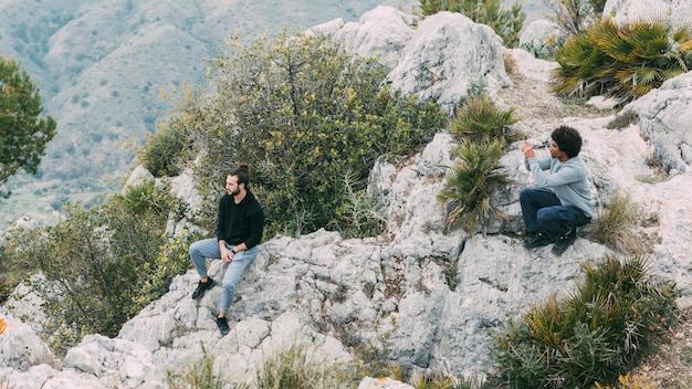 Uomo che si siede sulla roccia in natura