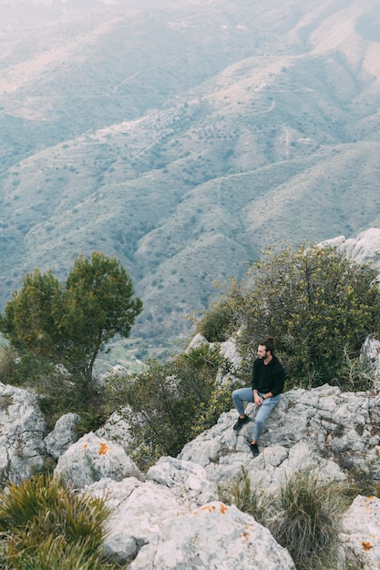 Uomo che si siede sulla roccia in natura