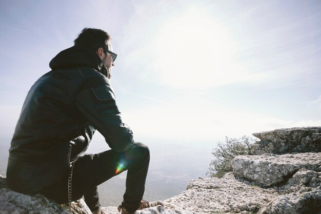 Uomo che si siede sulla roccia