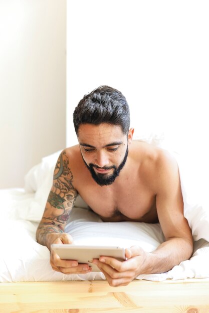 Uomo che si trova sul letto utilizzando la tavoletta digitale