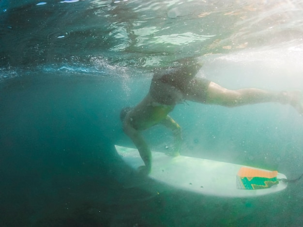 Uomo che si tuffa con tavola da surf sott&#39;acqua