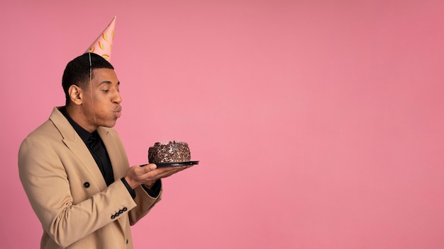 Uomo che soffia candele su una torta di compleanno