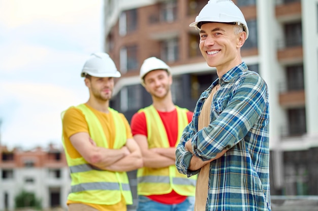 Uomo che sorride alla telecamera e i lavoratori dietro