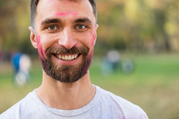 Uomo che sorride con la faccia dipinta per holi