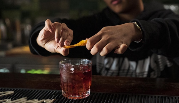 Uomo che spreme un limone sul suo whisky in un bar