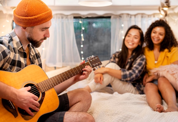 Uomo che suona la chitarra e donne in ascolto