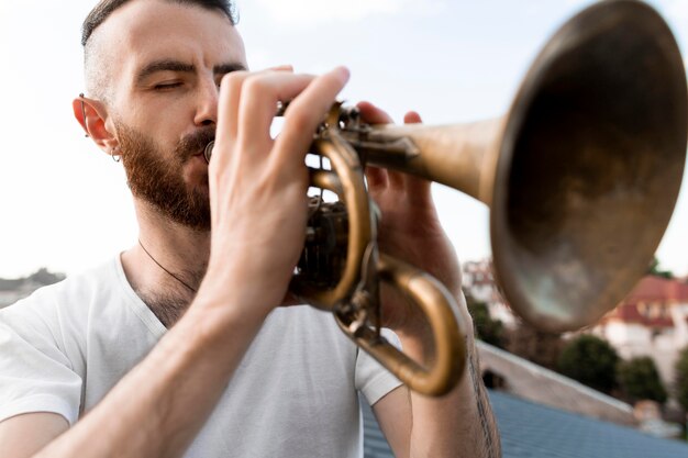 Uomo che suona la cornetta all'aperto