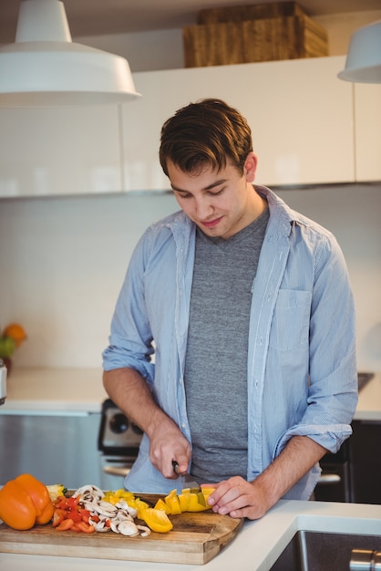 Uomo che taglia le verdure in cucina