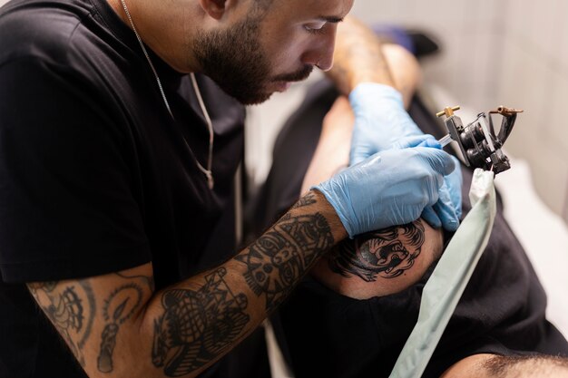 Uomo che tatua con i guanti ad alto angolo