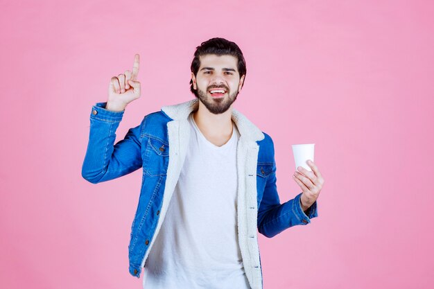 Uomo che tiene e presenta una nuova tazza di caffè usa e getta