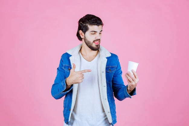 Uomo che tiene e presenta una nuova tazza di caffè usa e getta