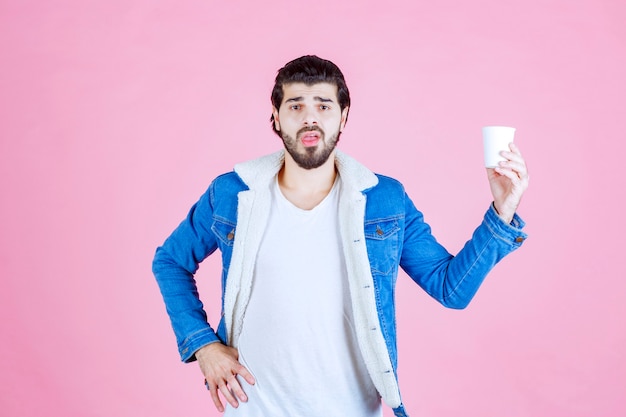 Uomo che tiene e presenta una nuova tazza di caffè usa e getta