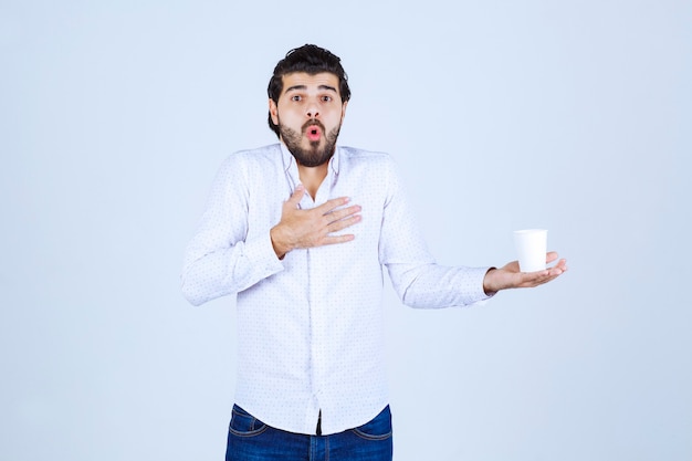 Uomo che tiene e promuove una tazza di caffè o un caffè