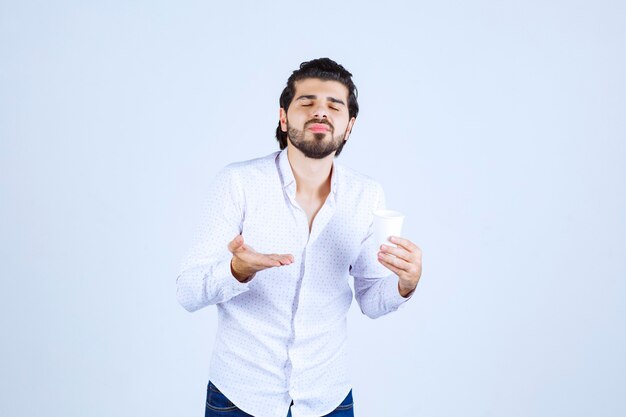 Uomo che tiene e promuove una tazza di caffè o un caffè