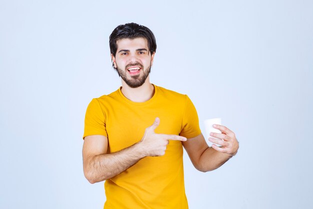 Uomo che tiene e promuove una tazza di caffè.