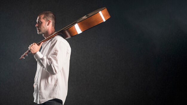 Uomo che tiene la chitarra acustica in studio