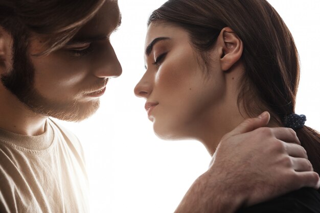 Uomo che tiene la mano sul collo della donna. Occhi chiusi. Bacio dolce.