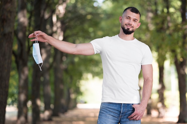 Uomo che tiene la sua maschera medica accanto a lui