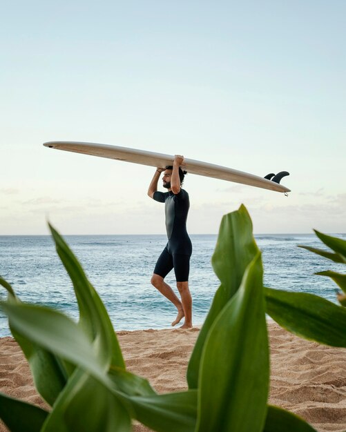 Uomo che tiene la sua tavola da surf