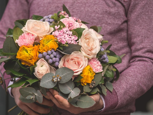 Uomo che tiene un bouquet romantico di fiori di selezione mista e pronto ad offrire