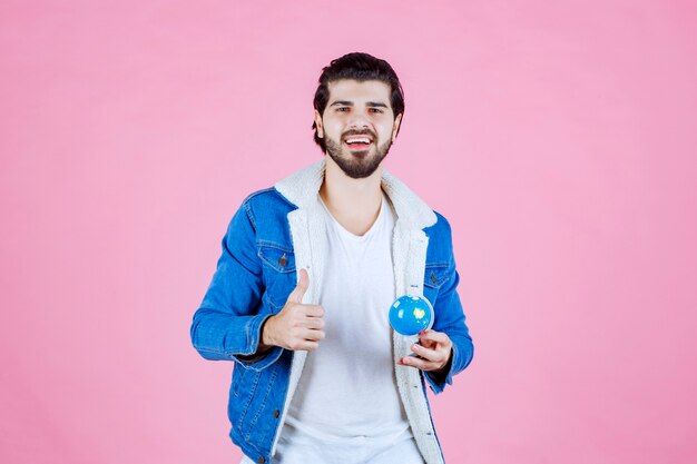 Uomo che tiene un mini globo e mostra un segno di divertimento