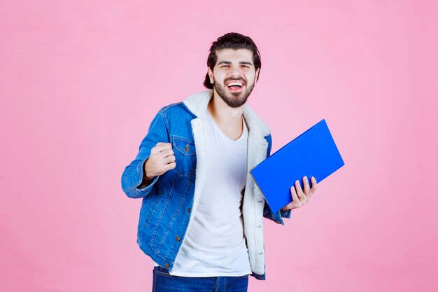 Uomo che tiene una cartella blu e mostra il pugno