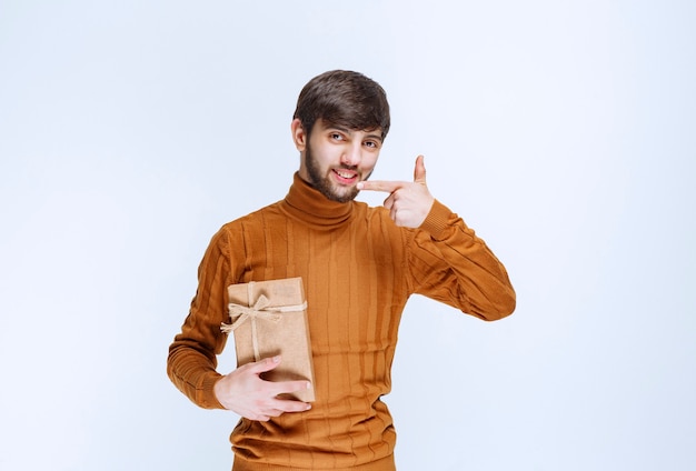 Uomo che tiene una scatola regalo di cartone e la presenta