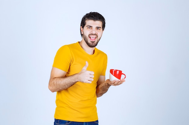 Uomo che tiene una tazza da caffè e si gode il gusto.