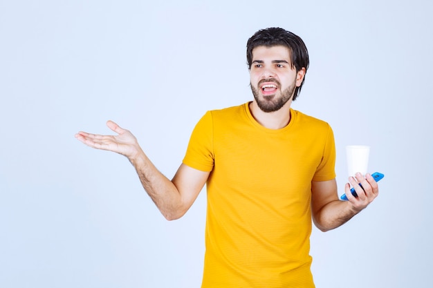 Uomo che tiene una tazza di caffè e fa una presentazione usando la mano aperta.