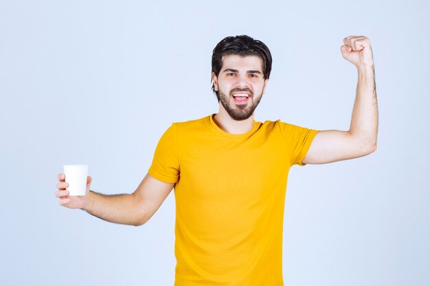 Uomo che tiene una tazza di caffè e mostra il suo potere.