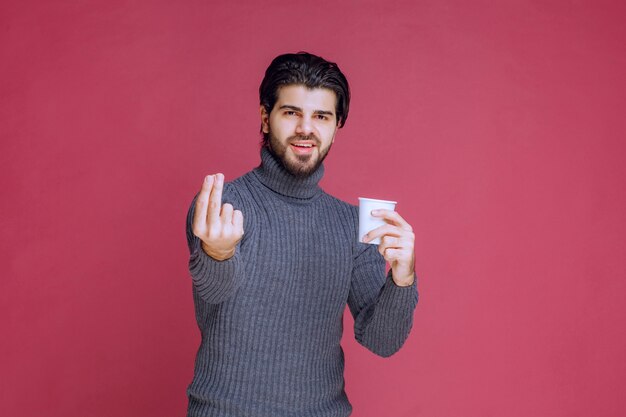 Uomo che tiene una tazza di caffè usa e getta e fa segno di godimento.