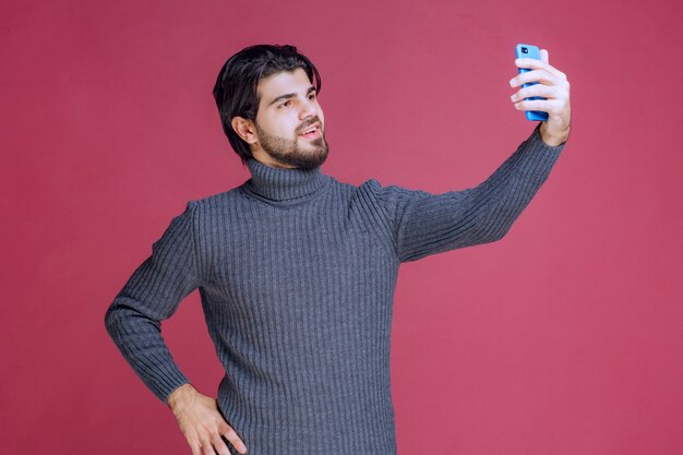 Uomo che tiene uno smartphone, effettua una videochiamata o prende selfie.