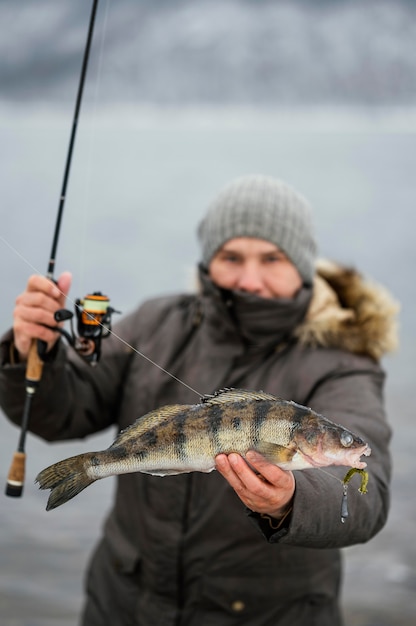 Uomo che tiene vittoriosamente un pesce che ha catturato