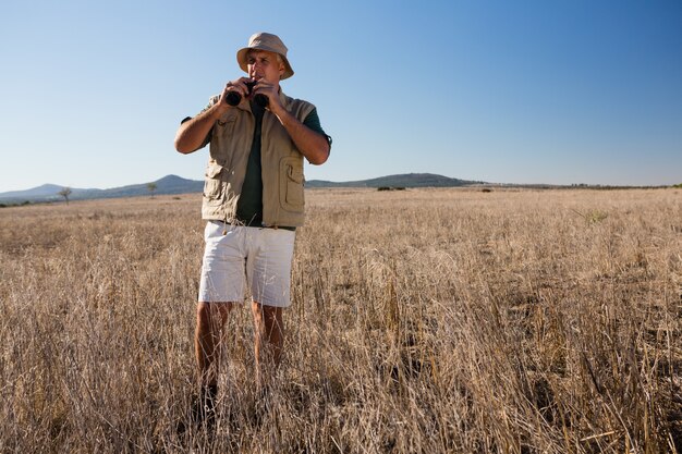 Uomo che usando binoculare sul paesaggio