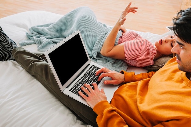 Uomo che utilizza computer portatile vicino a donna insoddisfatta