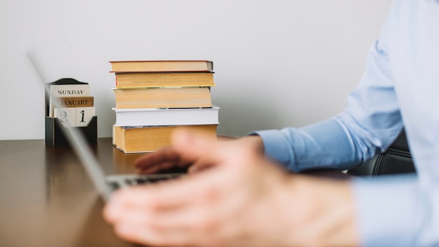 Uomo che utilizza computer portatile vicino a libri