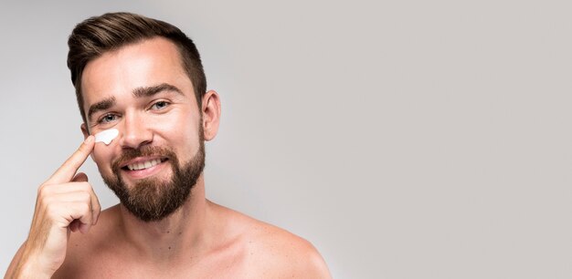 Uomo che utilizza crema per il viso con copia spazio